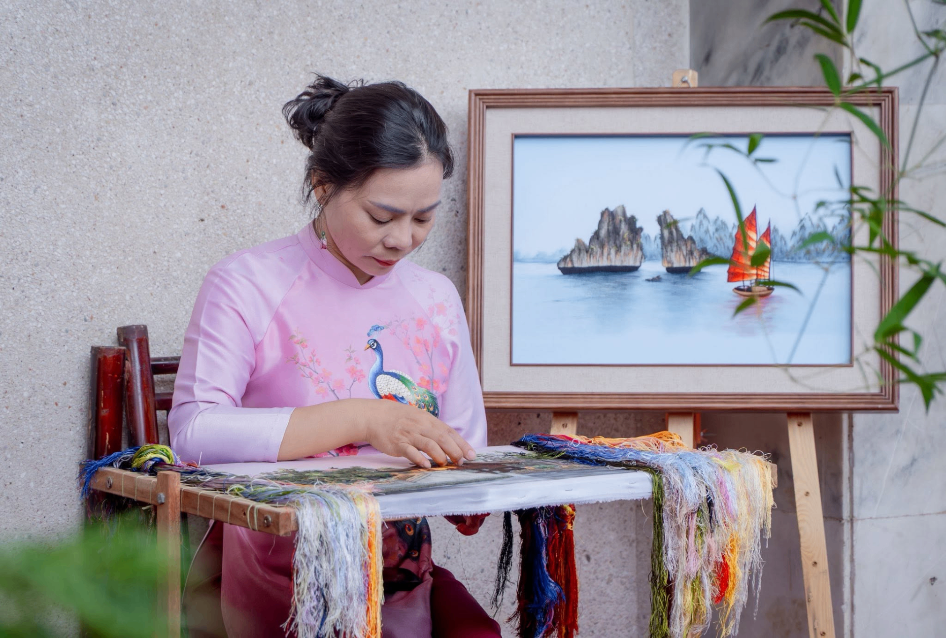 Master artisan hand embroidering a colorful silk piece on a wooden frame